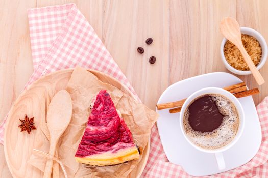 Homemade raspberry cake with cup of coffee on wooden background.