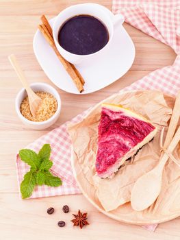 Homemade raspberry cake with cup of coffee on wooden background.
