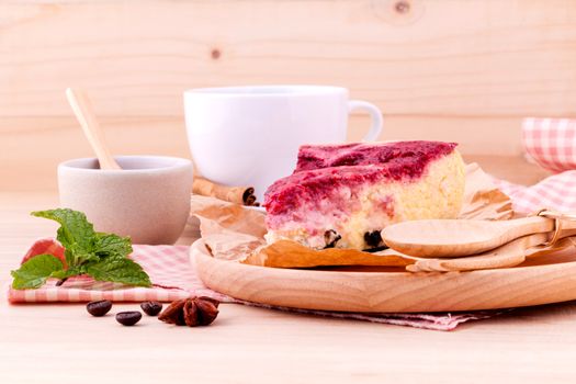 Homemade raspberry cake with cup of coffee on wooden background.