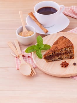 Homemade dark chocolate cake with cup of coffee on wooden background.