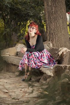 View of pinup young woman in vintage style clothing on a city park.