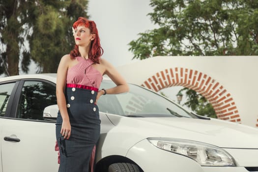 View of pinup young woman in vintage style clothing next to a white car.