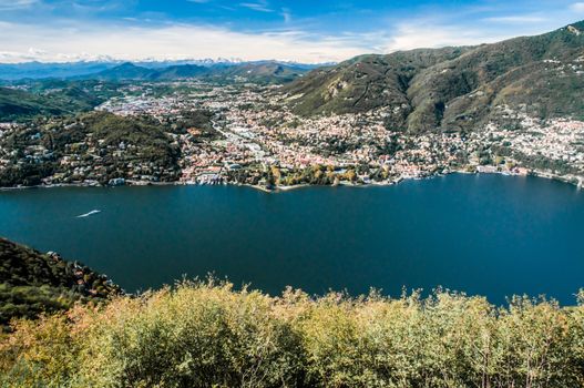 A view of Como in Italy over lake Como from high up above. In the distance the snow covered alps are visible.