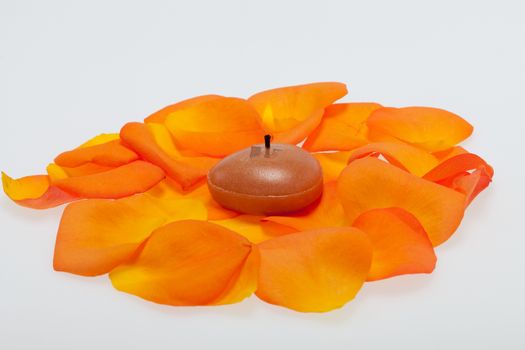 Spilt petals of the orange-rose around the aromatic candle