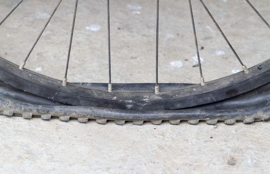 old Bicycle wheel with flat tyre on the concrete road
