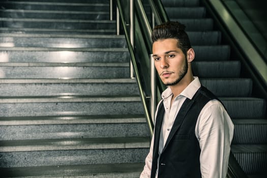 Profile shot of handsome young man inside train station looking at camera