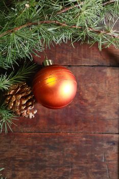 Christmas decoration. Pinecone and glass ball near spruce twigs on old wooden background