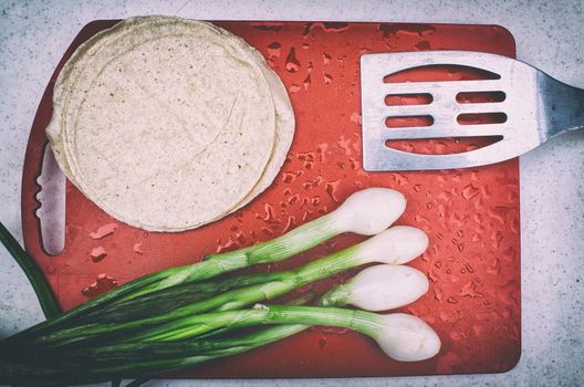 Photograph of some onions, tortillas, a spatula and a cutting board