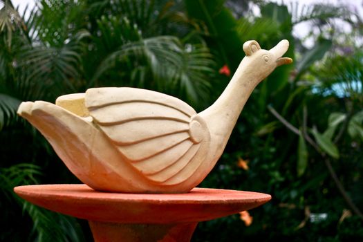 Duck Statue on tray with plants blur background