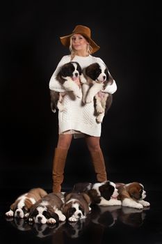 Young woman with seven puppies on a black studio background