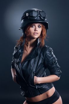 Young woman in leather jacket and helmet on a studio background