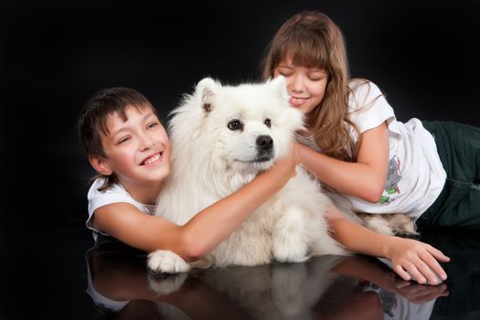 Teenaged girl and boy with a white Samoyed dog in the studio