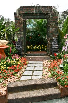 Door with old men statue and flowers, stones, plants