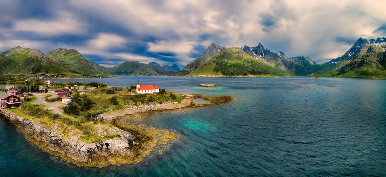 Scenic aerial panorama of Sildpollnes Church on Lofoten islands surrounded by fjords and magnificent mountain peaks, Norway