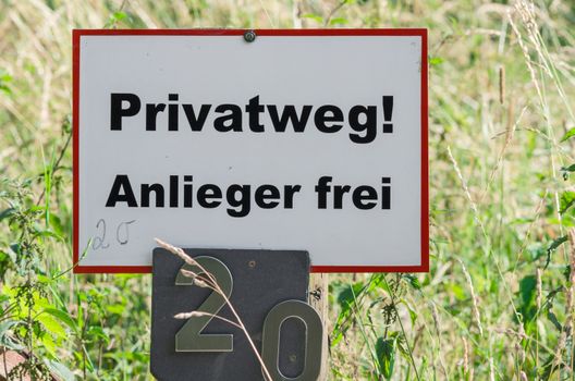 White sign with the word free private way, riparian, in the background green meadow.