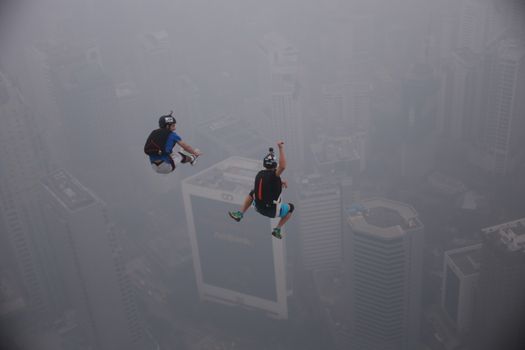MALAYSIA, Kuala Lumpur: Base jumper pair leap into haze	Heavy haze didn't deter the 120 thrill-seeking base jumpers as they leapt into the foggy abyss off Kuala Lumpur Tower on October 3, 2015.  	The participants were joining others across the world on the 15th�International Base Jump Day. 