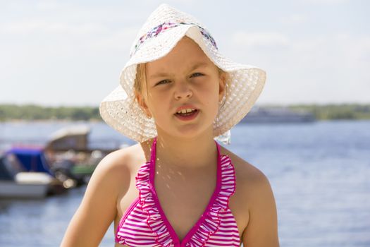 Cute girl in pink swimsuit and white hat