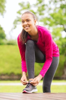 sport, exercise, park and lifestyle concept - smiling african american woman exercising outdoors
