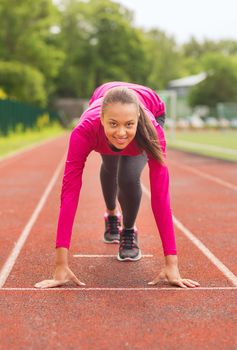 fitness, sport, training and lifestyle concept - smiling african american woman running on track outdoors