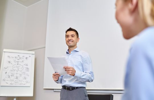 business, people and planning concept - smiling businessman and woman with papers meeting on presentation in office