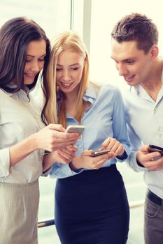 business and technology concept - smiling business team with smartphones in office