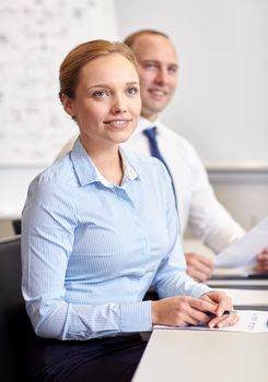 business, people and technology concept - smiling business team with papers meeting in office