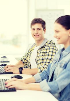 education, technology and school concept - smiling boy with girl in computer class at school