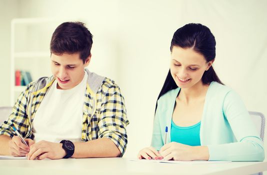 education and school concept - two smiling students with textbooks at school