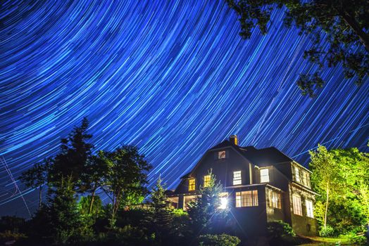 A time exposure of star trails swirling above a house in Miane