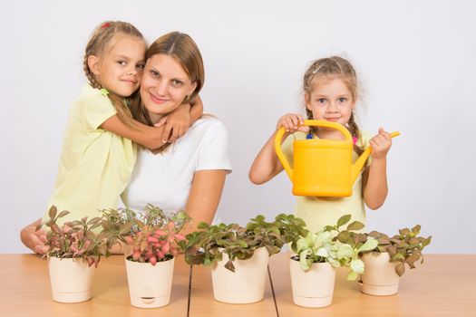 Mother and two daughters, four and six years of caring and watering potted plants