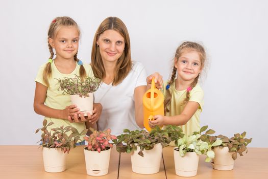 Mother and two daughters, four and six years of caring and watering potted plants