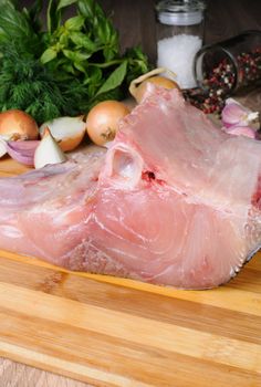 Raw piece (steak) carp on wooden board with fresh herbs and spices