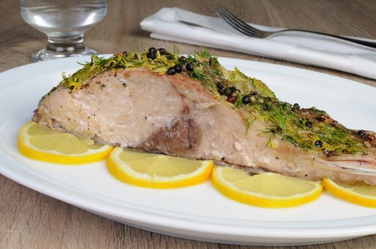Baked piece of carp with lemon dill sauce on a plate