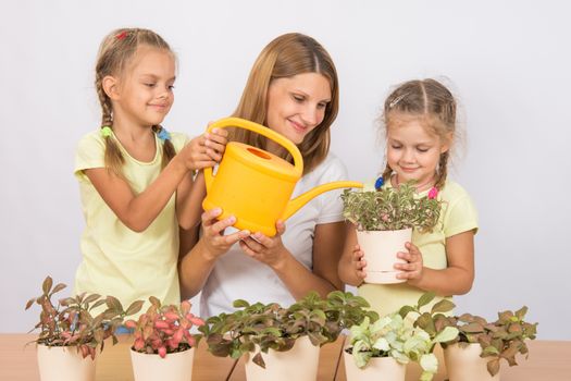 Mother and two daughters, four and six years of caring and watering potted plants