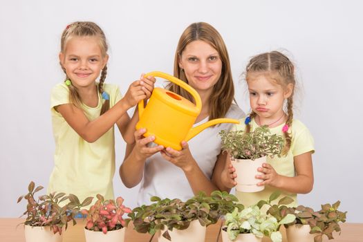 Mother and two daughters, four and six years of caring and watering potted plants