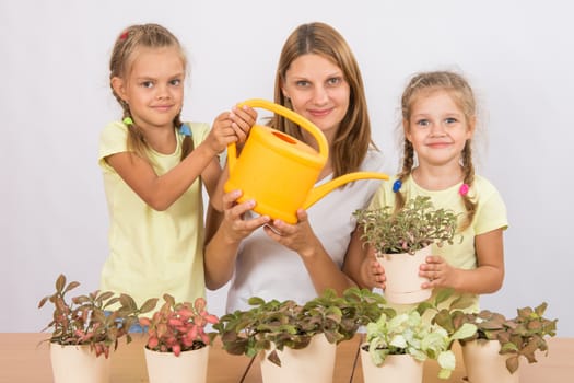 Mother and two daughters, four and six years of caring and watering potted plants