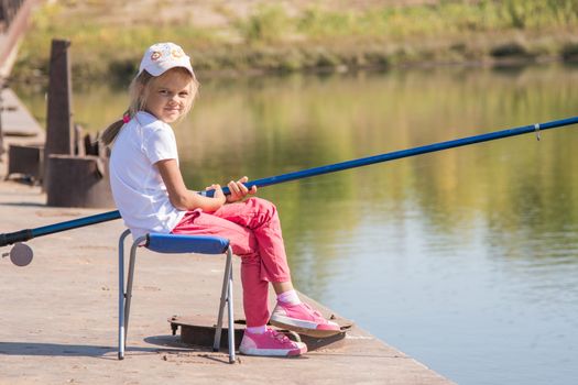 Six year old girl fishing from a bridge on a clear sunny day