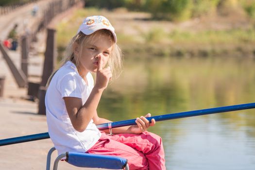 Six year old girl fishing from a bridge on a clear sunny day