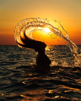 silhouette of a girl splashing water with hair