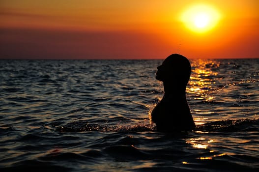 silhouette of a girl in ocean on sunset