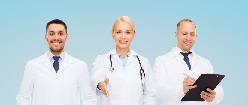 healthcare, people and medicine concept - group of doctors with stethoscope and clipboard making handshake gesture over blue background