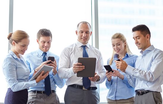 business, teamwork, people and technology concept - business team with tablet pc computers and smartphones meeting in office