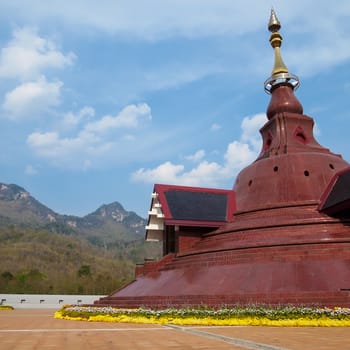 Kanchanaburi, Thailand - March 5, 2011 : red brown pagoda of Sunanthawararam Temple among the mountains 