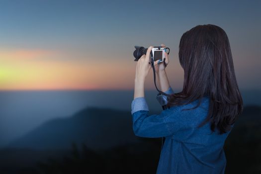 woman traveler wearing blue dress as photographer, take photo with camera in the morning outdoor