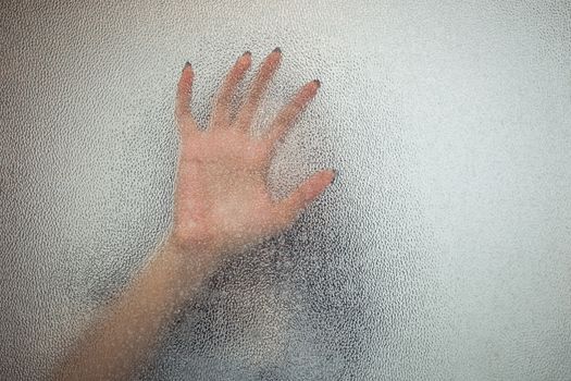 Halloween female hand behind transparent glass background as silhouette