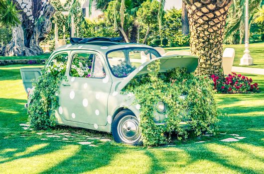 old little wedding car on green garden near flowers and leaves, vintage style