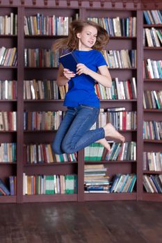 Woman holding books and jumping near the bookshelves