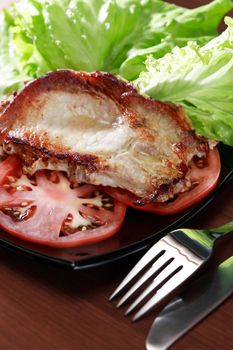 Piece of roasted meat on plate near vegetables and green salad