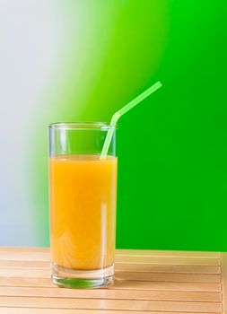 Orange juice with straw on the wood table on green background nutrition concept