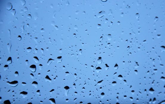 raindrops on window in front of blue backgrond